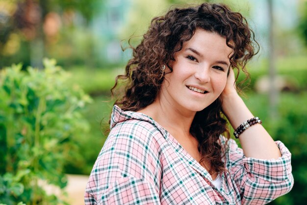 Una chica morena hipster con cabello largo y rizado se relaja al aire libre