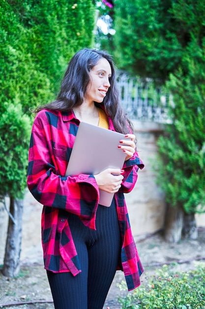 Chica morena con laptop en el parque