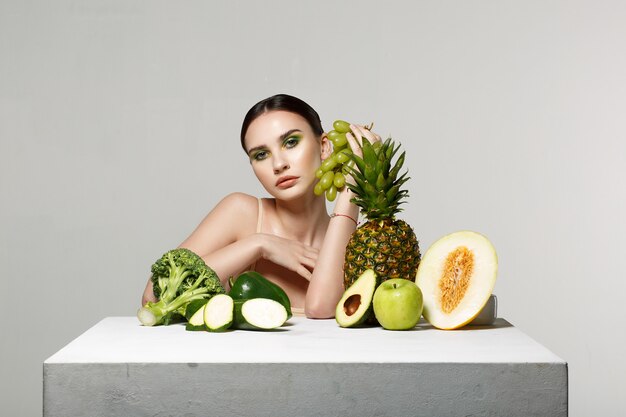 chica morena con maquillaje posando con frutas