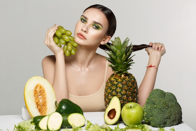 chica morena con maquillaje posando con frutas