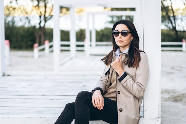 Chica morena de pelo bastante largo en gafas de sol relajantes al aire libre.