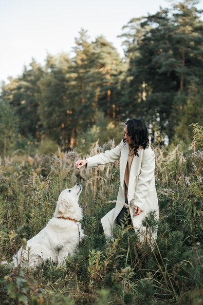 Foto chica morena con perro golden retriever blanco en el campo