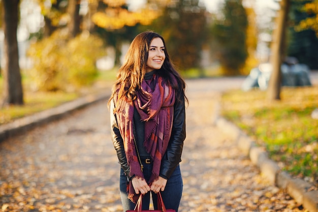 chica morena relajante en el parque durante el otoño