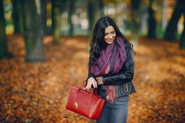 chica morena relajante en el parque durante el otoño