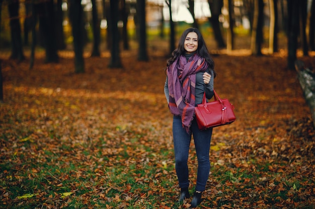 chica morena relajante en el parque durante el otoño