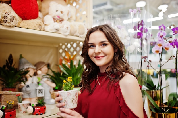 Chica morena en rojo comprar flores en la tienda de flores.