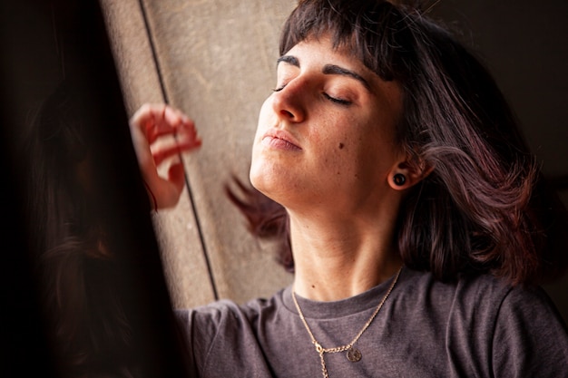 Chica morena sentada en una ventana de una casa vieja y abandonada