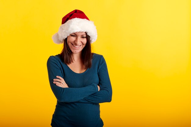 Una chica morena con un sombrero de Santa Claus con un fondo amarillo