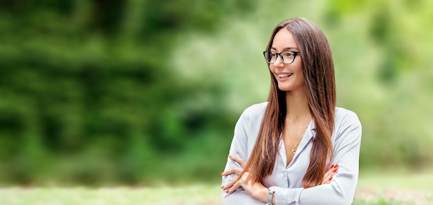 Chica morena sonriente con gafas contra el fondo del espacio de copia de la naturaleza