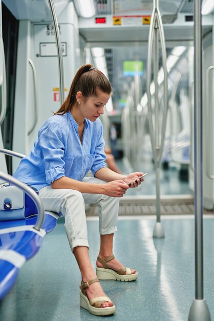 Chica morena con teléfono celular en el metro.