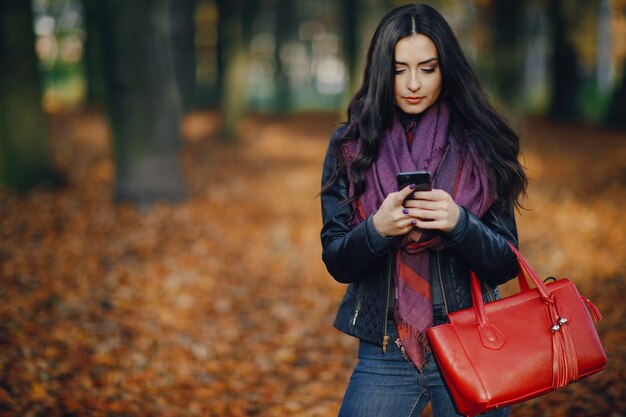 chica morena usando su teléfono mientras camina por el parque