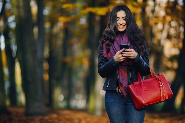 chica morena usando su teléfono mientras camina por el parque