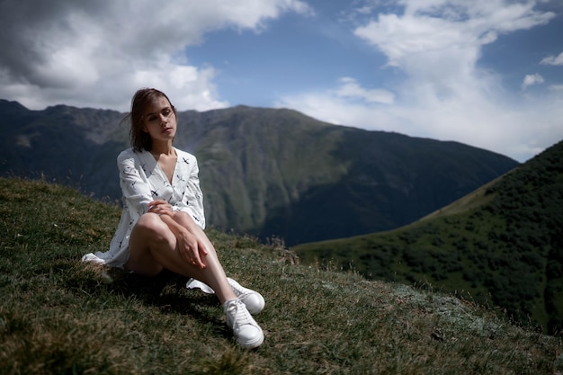 Chica morena con un vestido blanco se sienta en la montaña