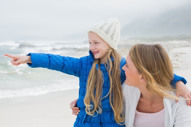 Chica mostrando algo a la madre en la playa