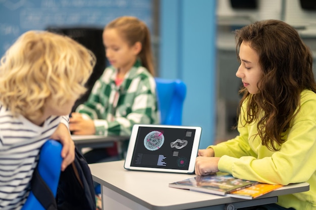 Chica mostrando la pantalla de la tableta con información educativa para el niño