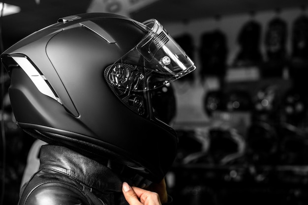 Foto chica motociclista en un casco de chaqueta negra mujer motociclista de maquillaje sexy hermosa en casco de moto deportiva sobre fondo negro primer plano retrato oscuro