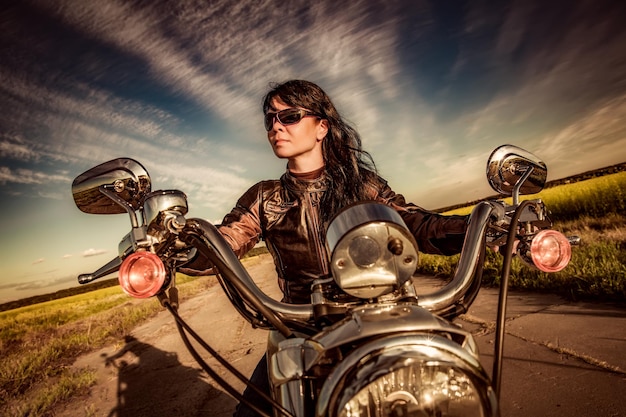 Chica motociclista en una chaqueta de cuero en una motocicleta