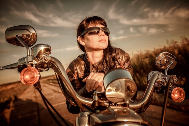 Chica motociclista con gafas de sol sentado en motocicleta. Filtro aplicado en postproducción.