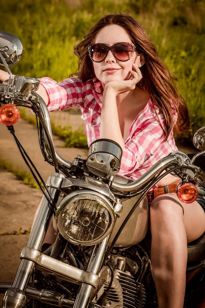 Chica motorista con gafas de sol sentado en motocicleta