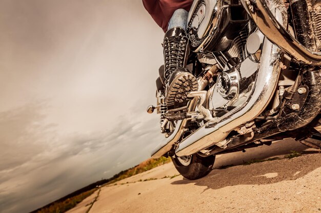 Chica motorista montando en una motocicleta. Vista inferior de las piernas con botas de cuero.