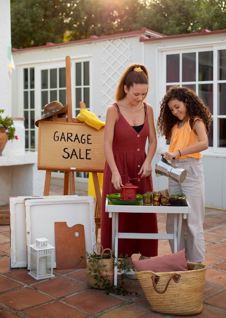 Foto chica y mujer de tiro completo en venta de garaje