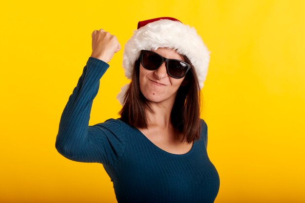 Una chica musculosa con un gorro de Papá Noel sobre un fondo amarillo