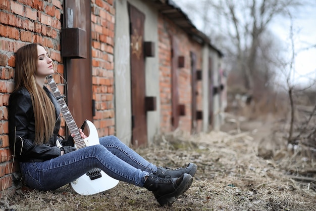 Una chica de músico de rock con una chaqueta de cuero con una guitarra.