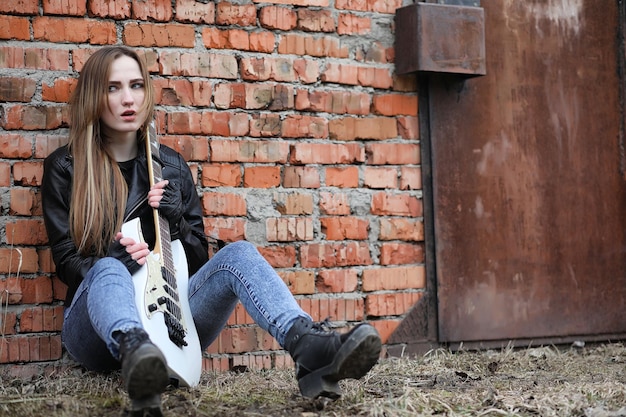 Una chica de músico de rock con una chaqueta de cuero con una guitarra.