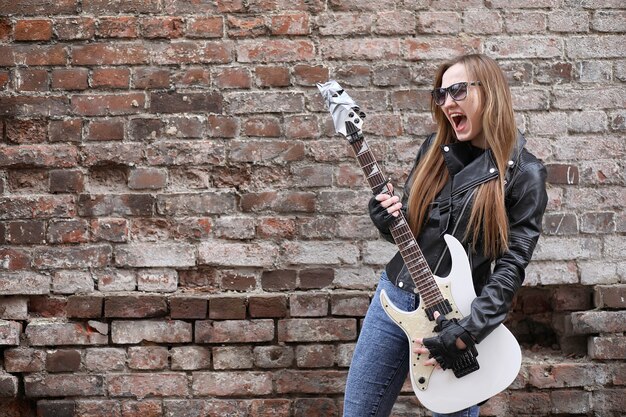 Foto una chica de músico de rock con una chaqueta de cuero con una guitarra.