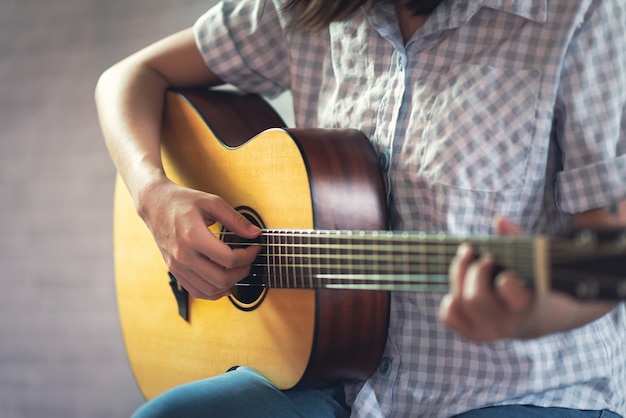 Chica músico tocando la guitarra acústica