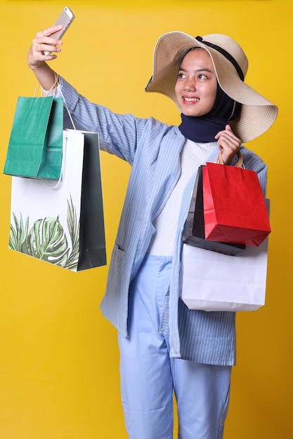 Chica musulmana con estilo en estilo casual toma una foto selfie mientras lleva bolsas de compras