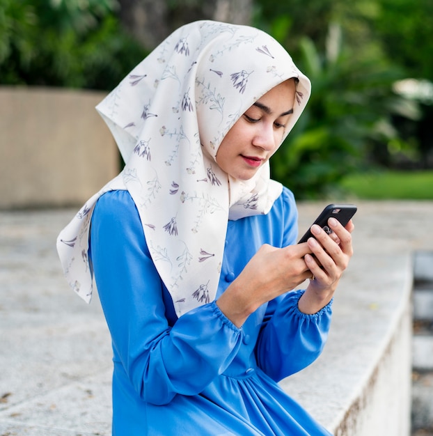 Chica musulmana usando un teléfono inteligente en el parque