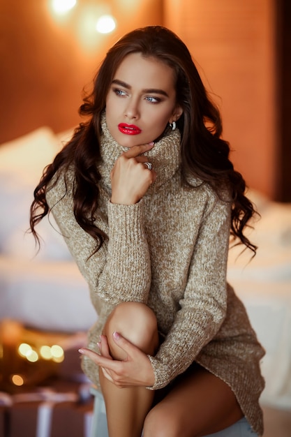 Chica muy elegante vestido con peinado y maquillaje sentado en el sofá. Retrato de glamour de moda.