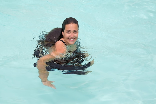 Chica nada con ropa en la piscina