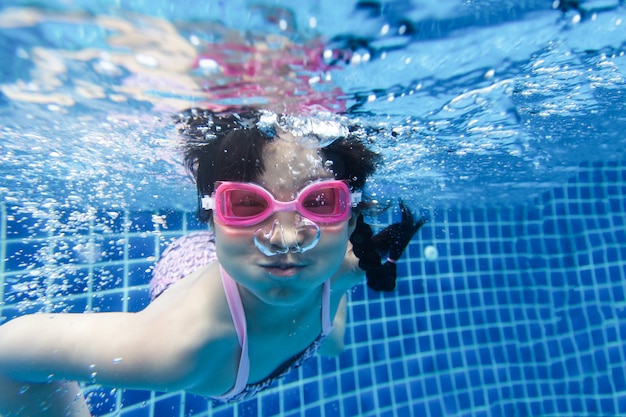 Chica nadando y buceando en la piscina azul