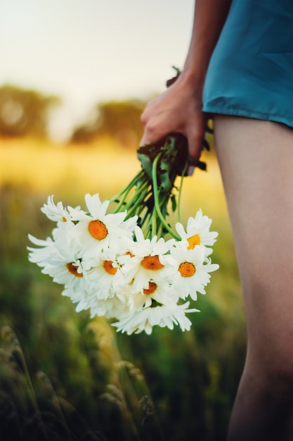 Chica en la naturaleza con ramo de margaritas en la mano. Concepto de romance y amor