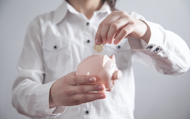 Chica de negocios poniendo monedas en la hucha. Ahorrando dinero