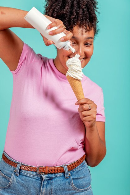 Chica negra comiendo un cono de helado sobre un fondo turquesa