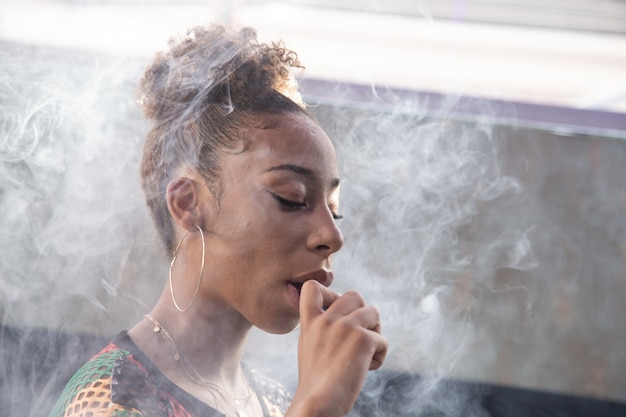 Chica negra fumando con un vapor