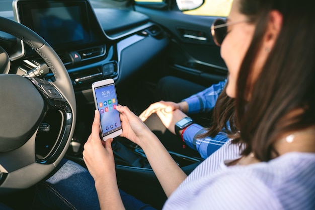 Chica y novio usando el móvil en el auto