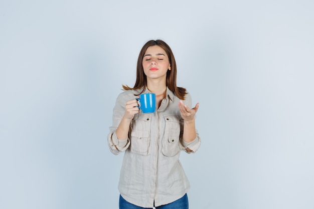 chica oliendo té en taza en camisa y mirando encantada.