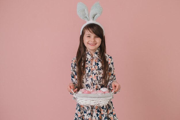 Chica con orejas de conejo sosteniendo una canasta de Pascua