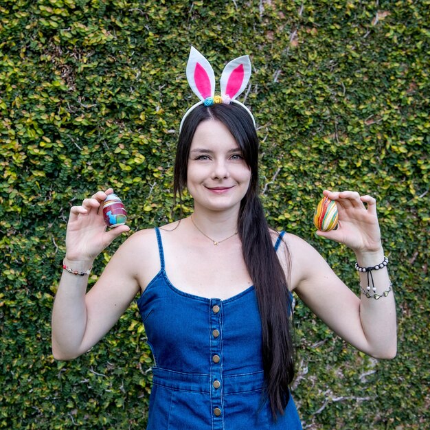 Chica con orejas de conejo sosteniendo coloridos huevos de Pascua