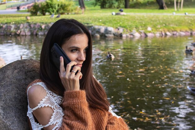 Una chica en la orilla del río está hablando por teléfono.