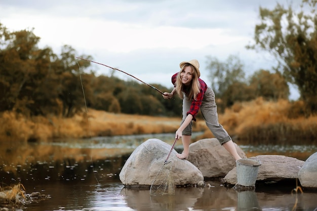 Chica en otoño con una caña de pescar