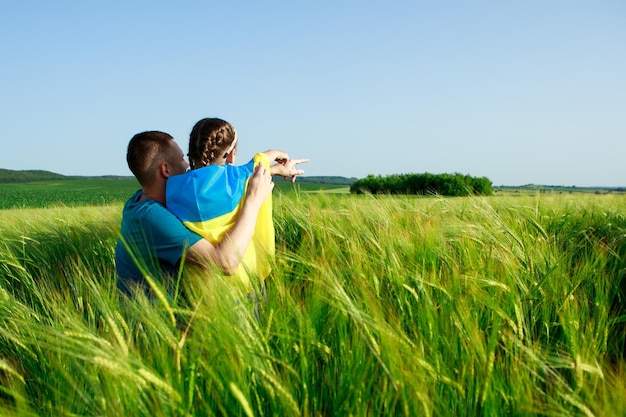 Chica con padre en un campo con bandera ucraniana