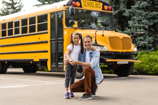 Foto chica con padre volviendo a la escuela cerca del autobús escolar