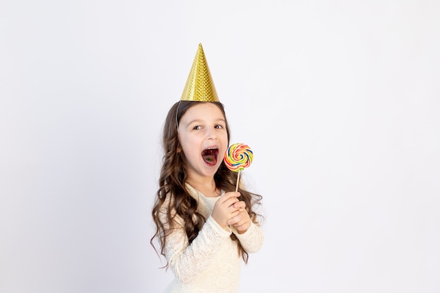 Chica con una paleta grande en una gorra sobre un fondo blanco.