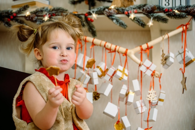 Chica con pan de jengibre de Navidad y regalos colgando de una rama