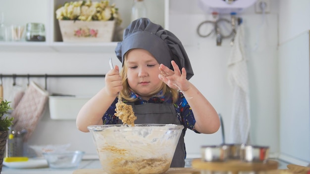 Chica panadera mezcla la mezcla para galletas con una cuchara grande de cerca